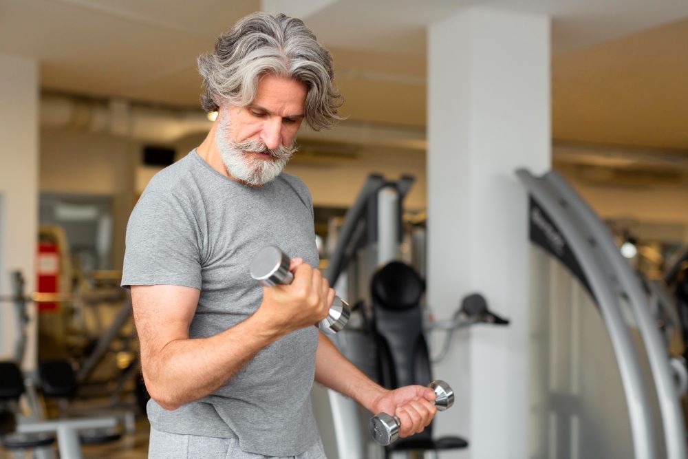 a man in a gray shirt training with dumbbells