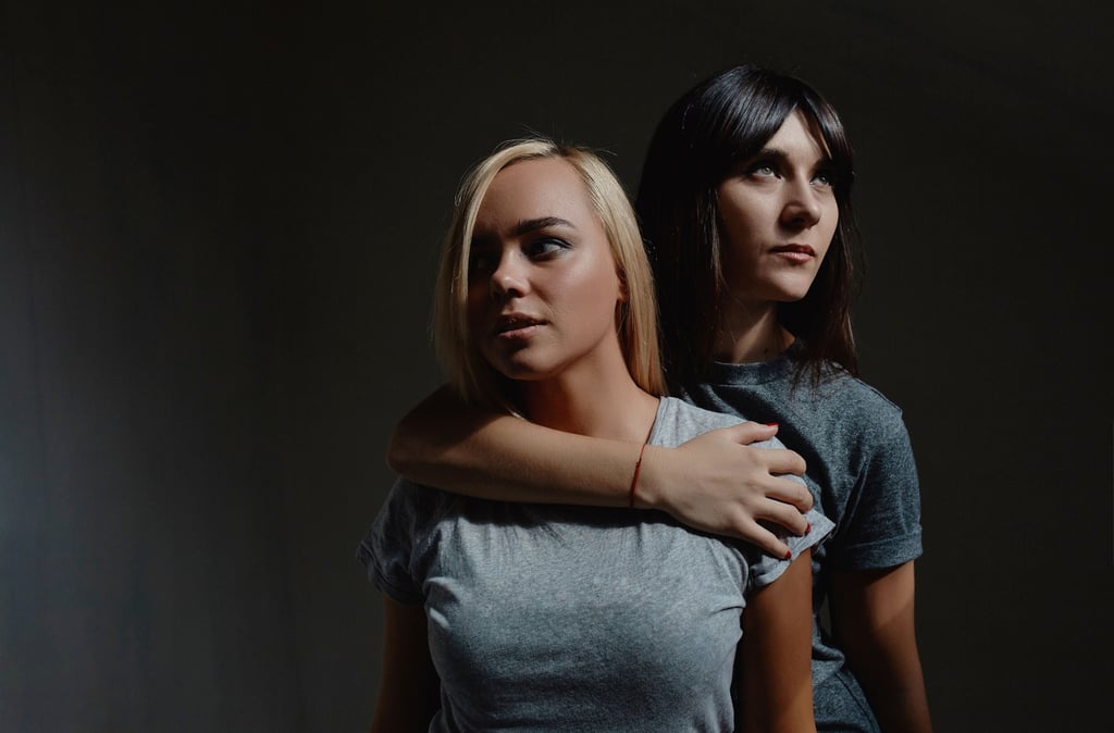 two women standing next to each other in a dark room