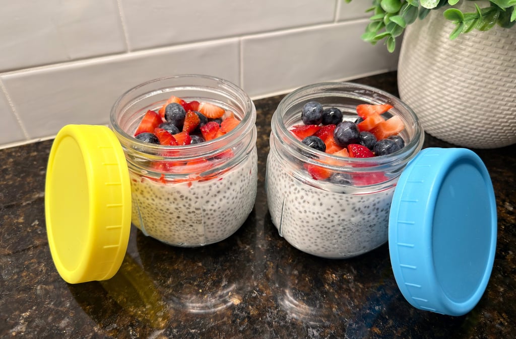 Two jars of chia pudding with protein powder, topped with fresh strawberries and blueberries.