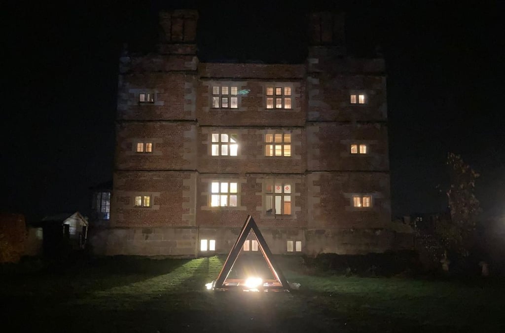 Soulton Hall seen at night with a large, steel pyramid in front