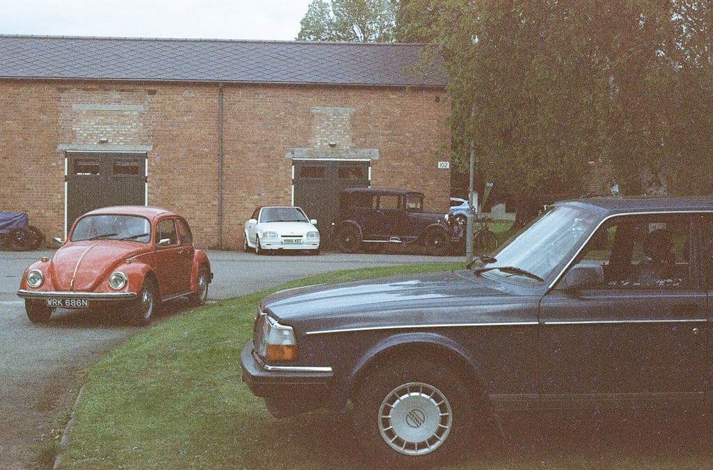 a selection of classic cars parked in front of a brick building