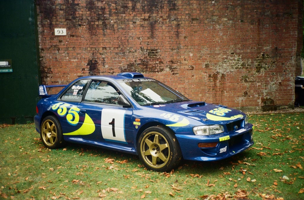 a Subaru Impreza rally car parked in front of a brick building