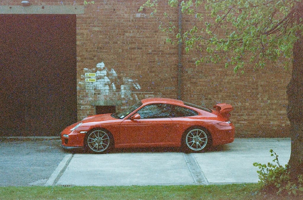 a red Porsche parked in front of a brick building