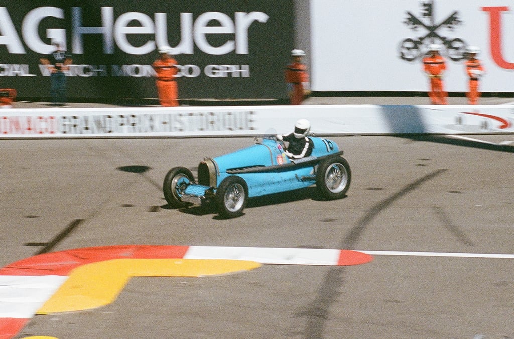 a man driving a blue race car on a track in Monaco