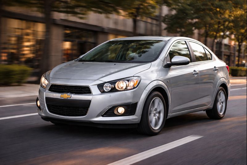 Chevrolet Sonic 2014 sedã rodando em rua asfaltada, visto de frente em ambiente urbano.