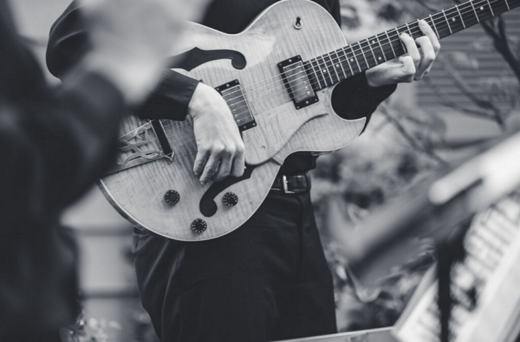 a black and white photo of a man playing guitar 