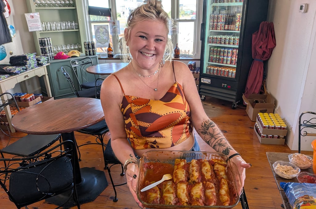 Smiling woman holding a tray of food surrounded by tables and chairs