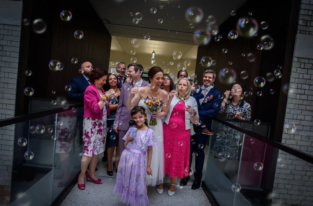 Smiling bride and wedding guests celebrating with bubbles at Lambeth Town Hall