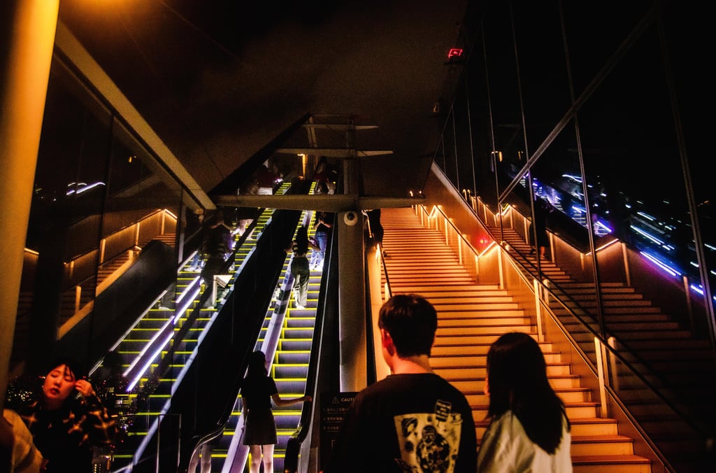 Shibuya Sky: a couple of people walking up stairs in a building