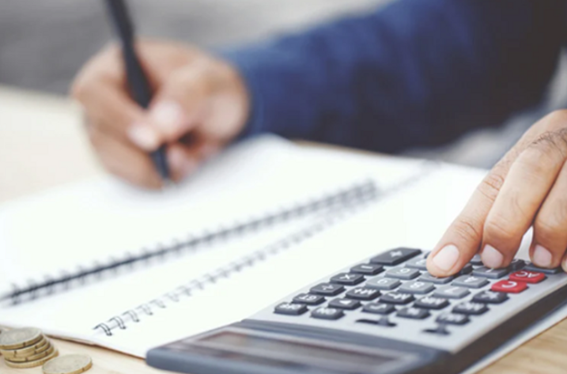 mãos digitando calculadora e fazendo anotações