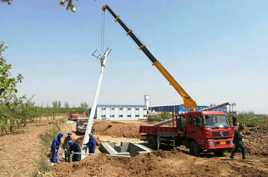 A telescopic boom truck mounted crane lifting a large object over a field.