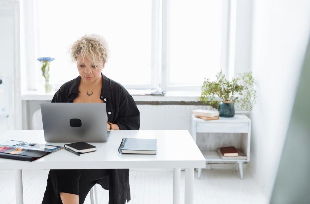 Person working on a laptop with a notebook and coffee, creating digital product ideas for beginners.