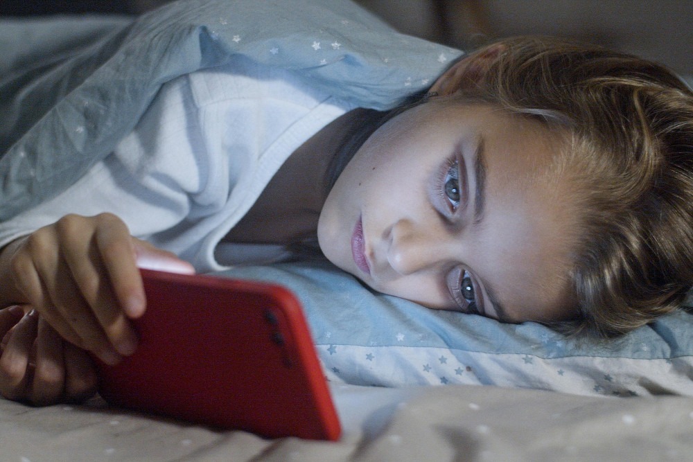 a young boy is laying on a bed with a red phone