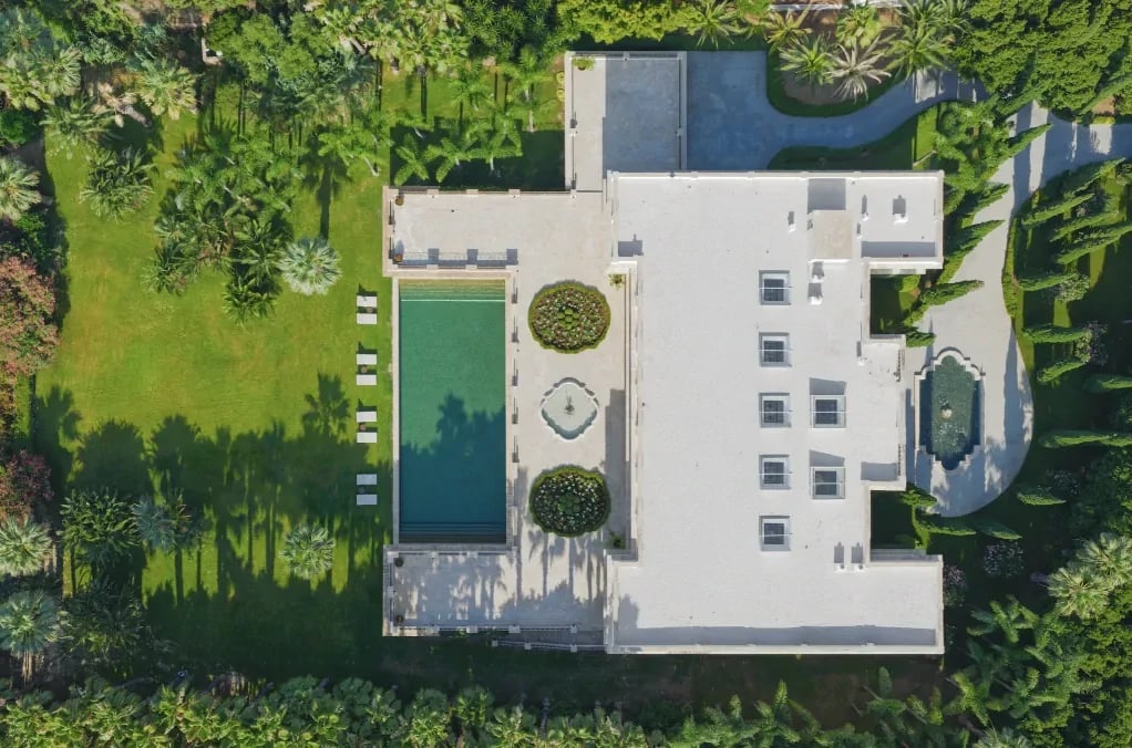 Aerial view of symmetrical estate with formal gardens and long pool