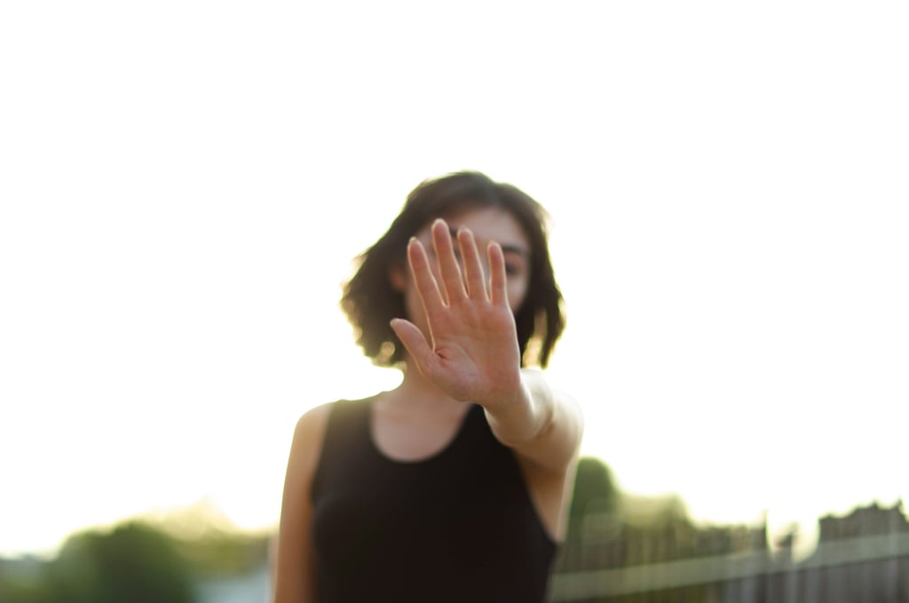 mulher jovem de cabelos escuros, imagem desfocada, mão a frente do rosto