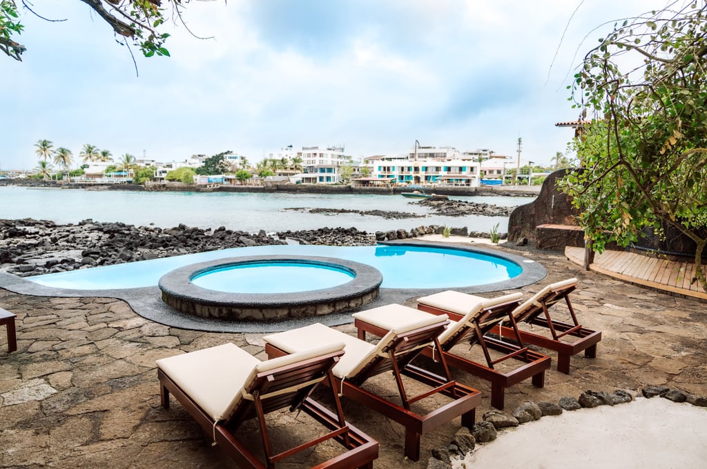 Oceanfront swimming pool and sun loungers at Villa Escalesia Galápagos, overlooking the rocky coastl