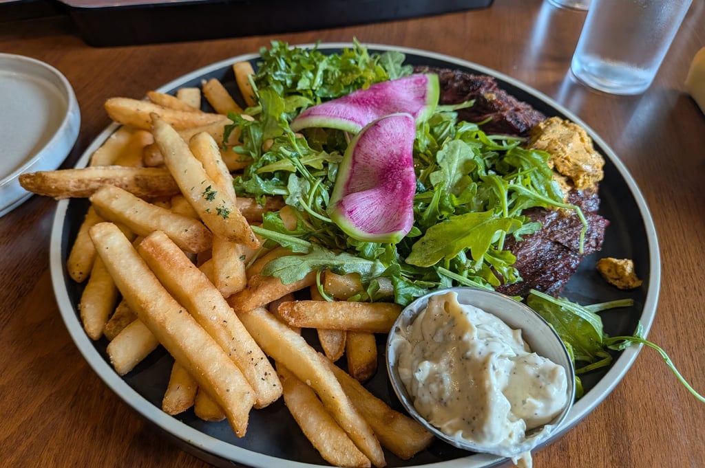 Steak frites platter served with crispy golden french fries, fresh arugula salad, and creamy dipping sauce.
