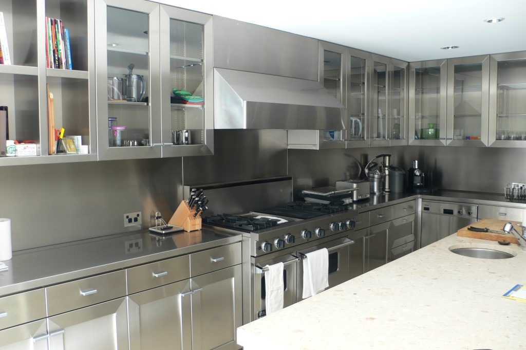 stainless steel kitchen with open shelving, glass doors, countertop and backsplash