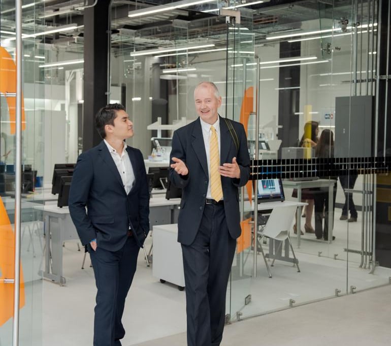 Jörg Grube mit Anzug, weißem Hemd und Krawatte mit einem anderen Geschäftsmann im Gespräch