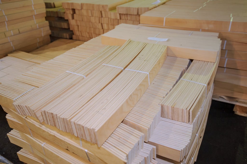 Bundled stacks of light-colored natural wood birch and beech bed slats in  warehouse.