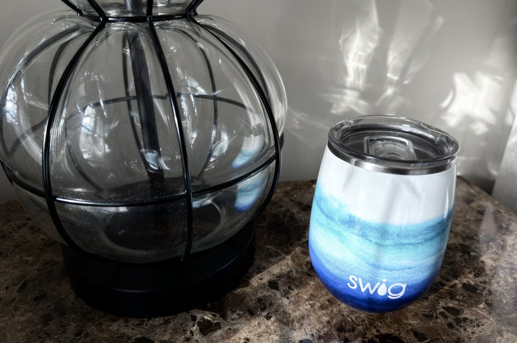 Swig tumbler with water resting on a nightstand beside a lamp creating a calm bedtime scene
