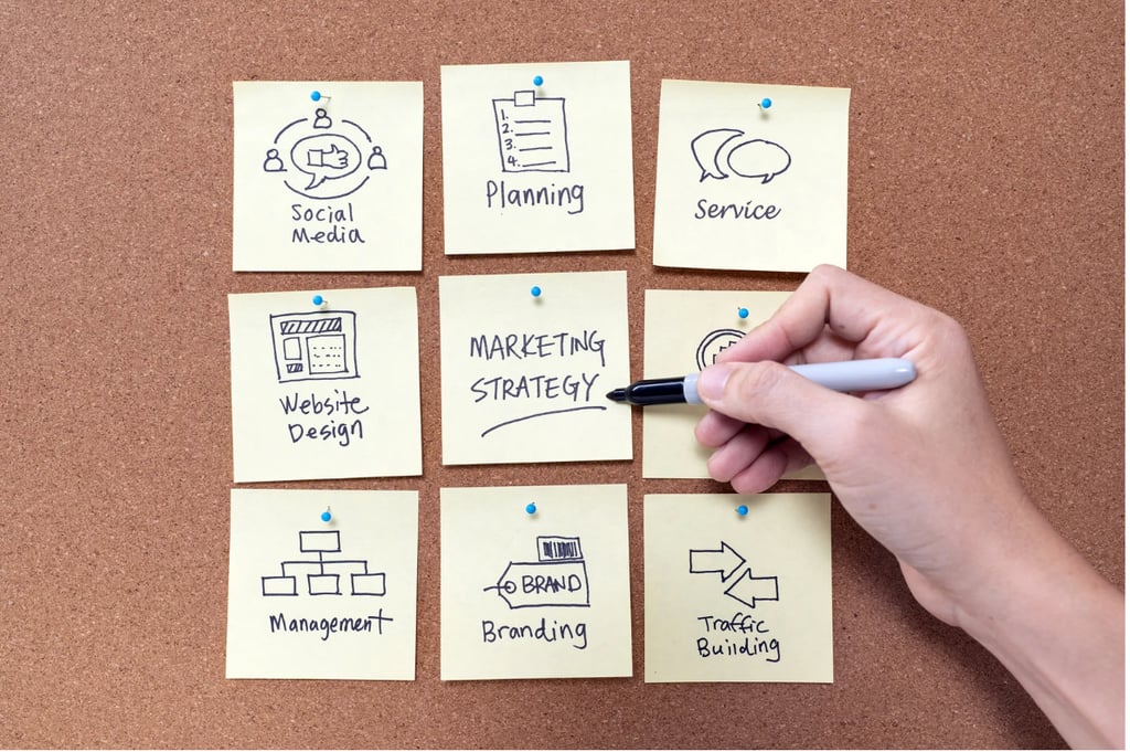 a person's hand holding a pen and writing on sticky notes
