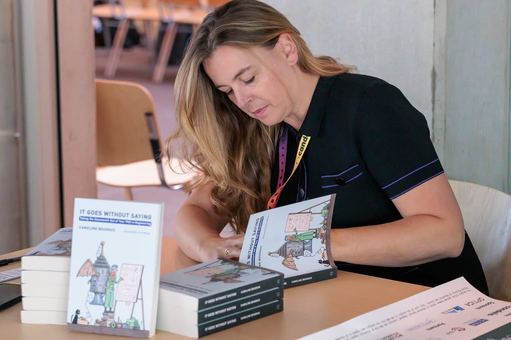 a woman is sitting at a table with books and a book