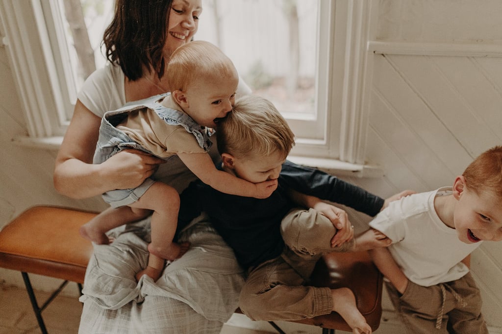 a woman holding a baby and two children
