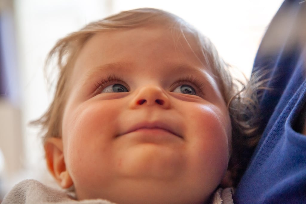 a baby is smiling and looking up her mom