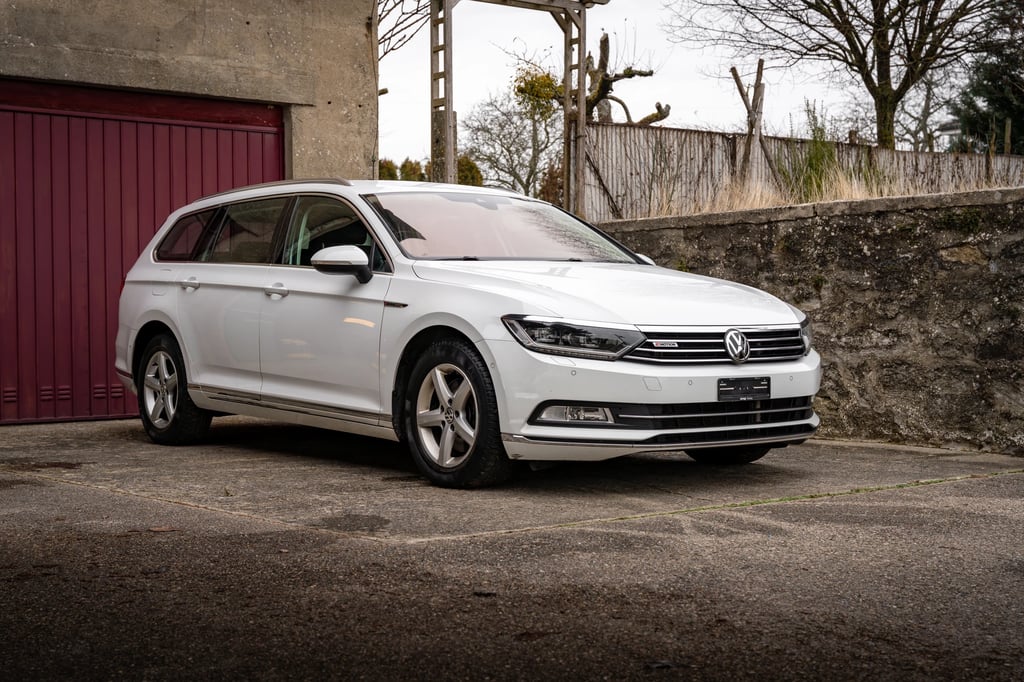 a white volkswagen passat parked in front of a red door