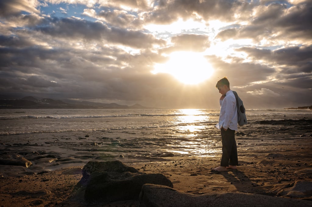 a man standing on a beach with a backpack