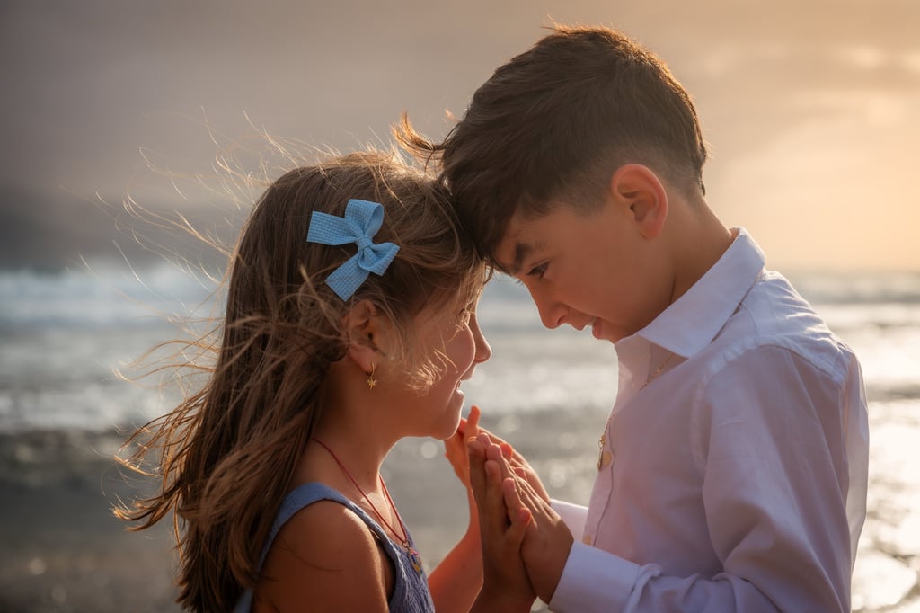 a boy and girl standing in front of a body of water
