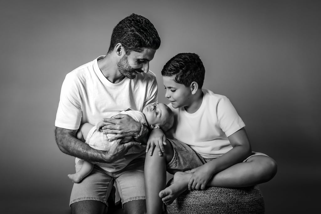 "Un retrato de familia en blanco y negro, padre con su hijo mayor y bebé en brazos"