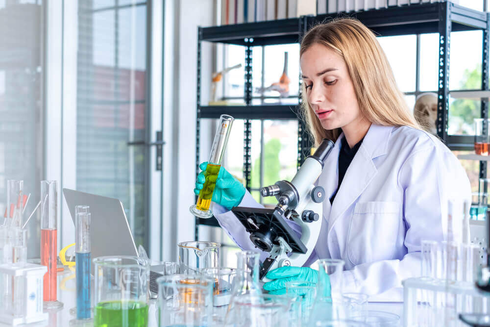 Profissional mulher biomédica fazendo análises de amostras clínicas.