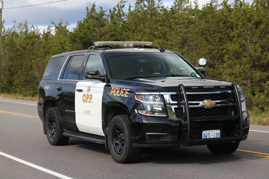 Black and white Ontario Provincial Police (OPP) Chevrolet Tahoe patrol SUV driving on a highway.