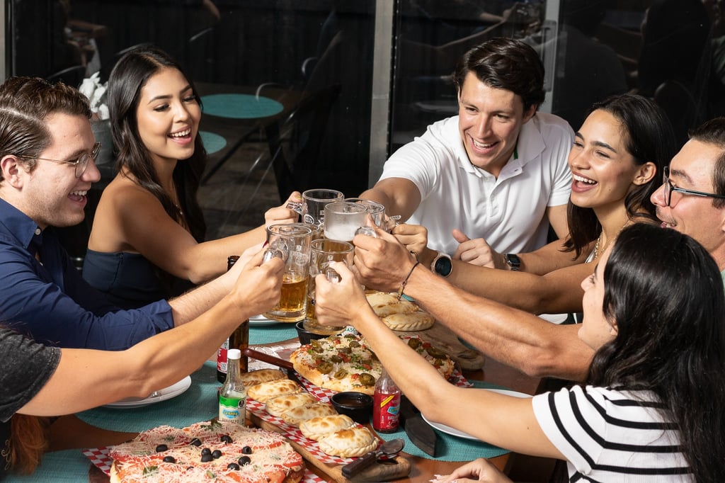 Fotografía de estilo de vida en Cancún. Grupo de amigos brindando con cerveza en restaurante.