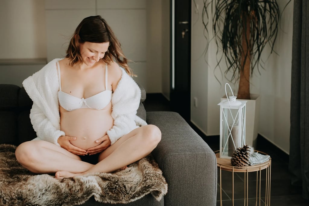 une femme enceinte assise sur son canapé 