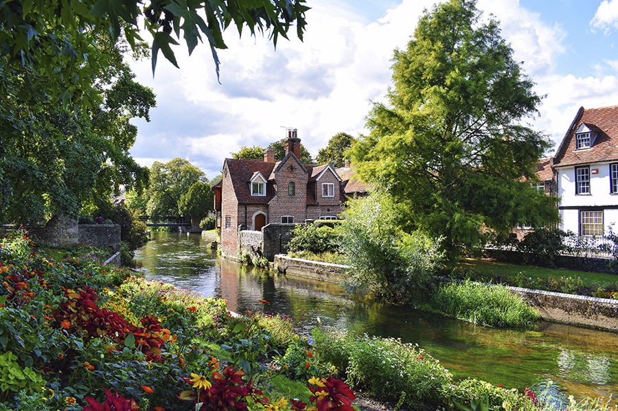 Maison en brique rouge sur les bord de la riviere Great Stour à Canterbury bordée de fleurs