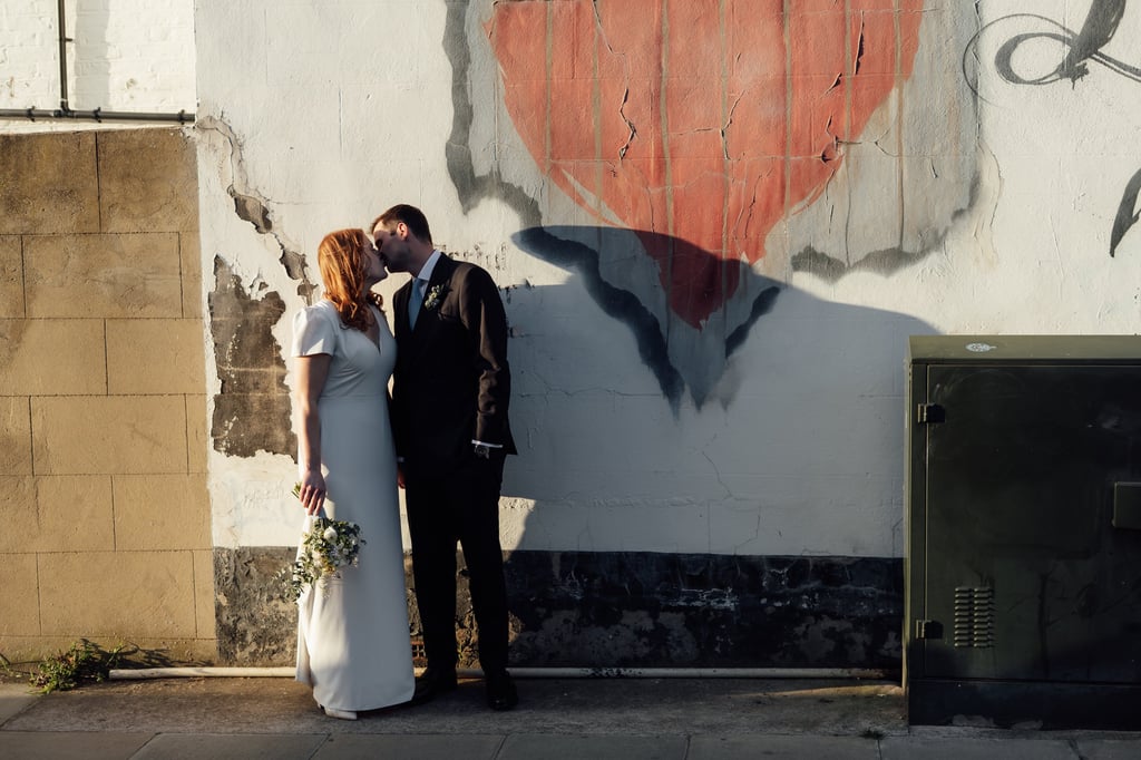 bride and groom kissing each other on the street during the golden hour 