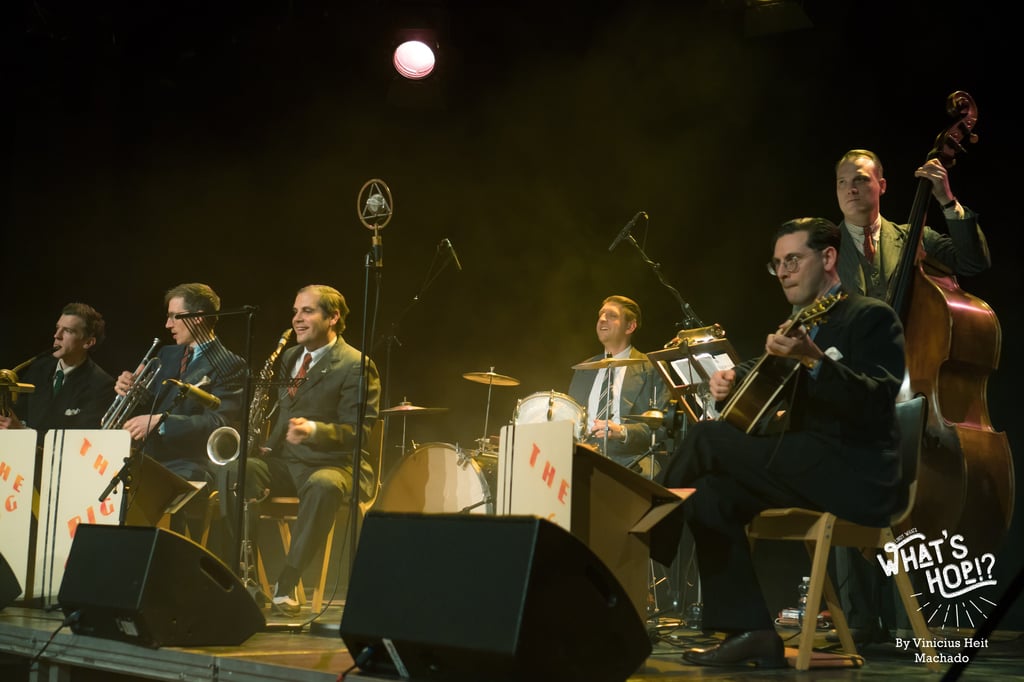 A vintage-style swing jazz band performing live on stage with brass instruments, drums, and double bass.