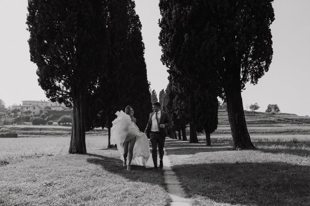 a bride and groom walking down a path in a field