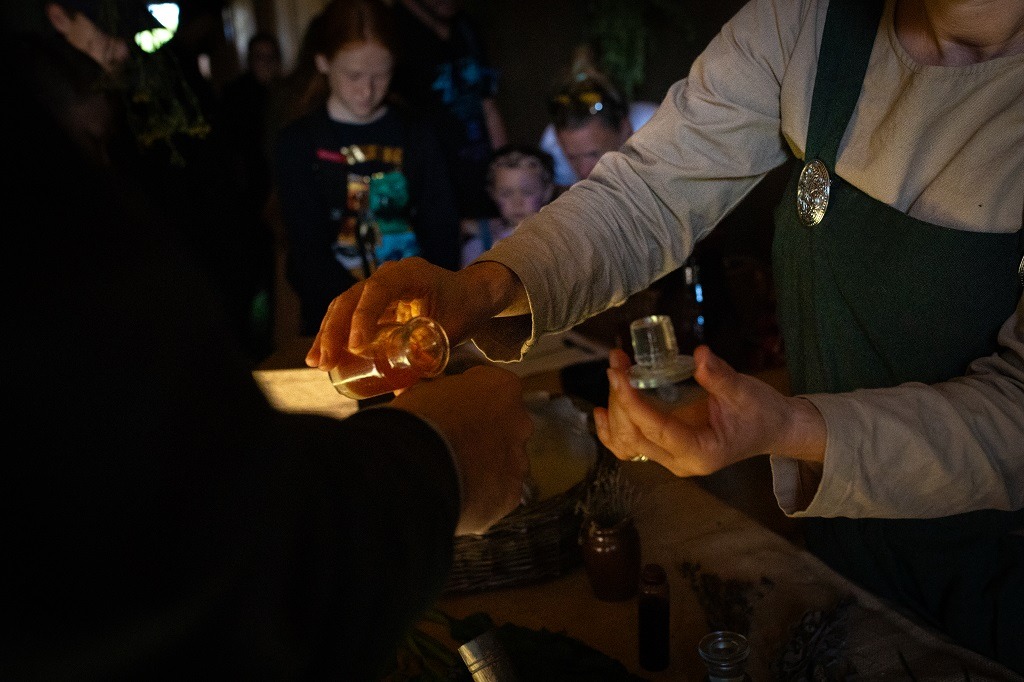 a person is holding a glass bottle places a drop of tincture onto the back of another person's hand