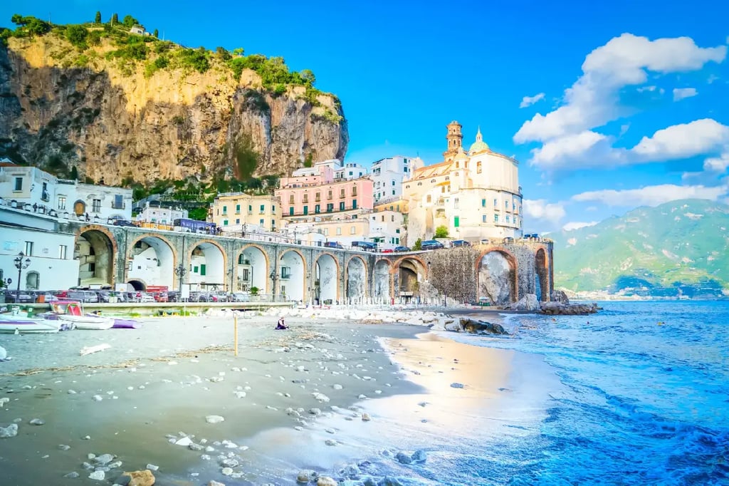 Colorful coastal buildings and arched bridges along the Amalfi Coast overlooking a sandy beach