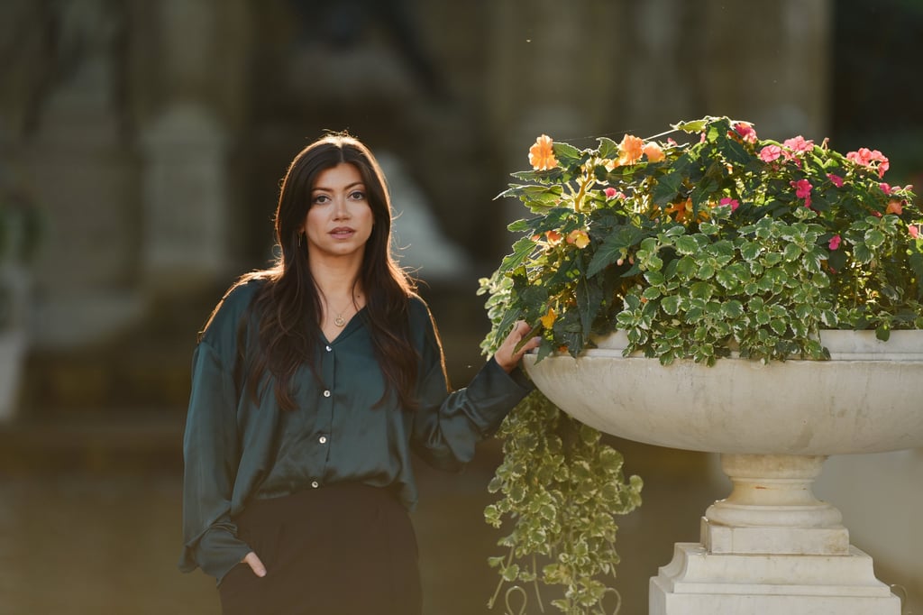 Une très belle femme pose devant une grande vasque fleurie, le soleil dans les cheveux