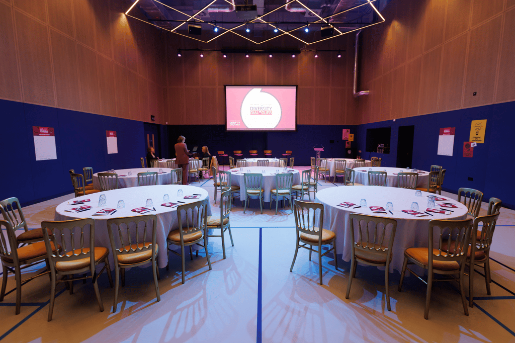 The Social Hub theater set up with round tables and a screen