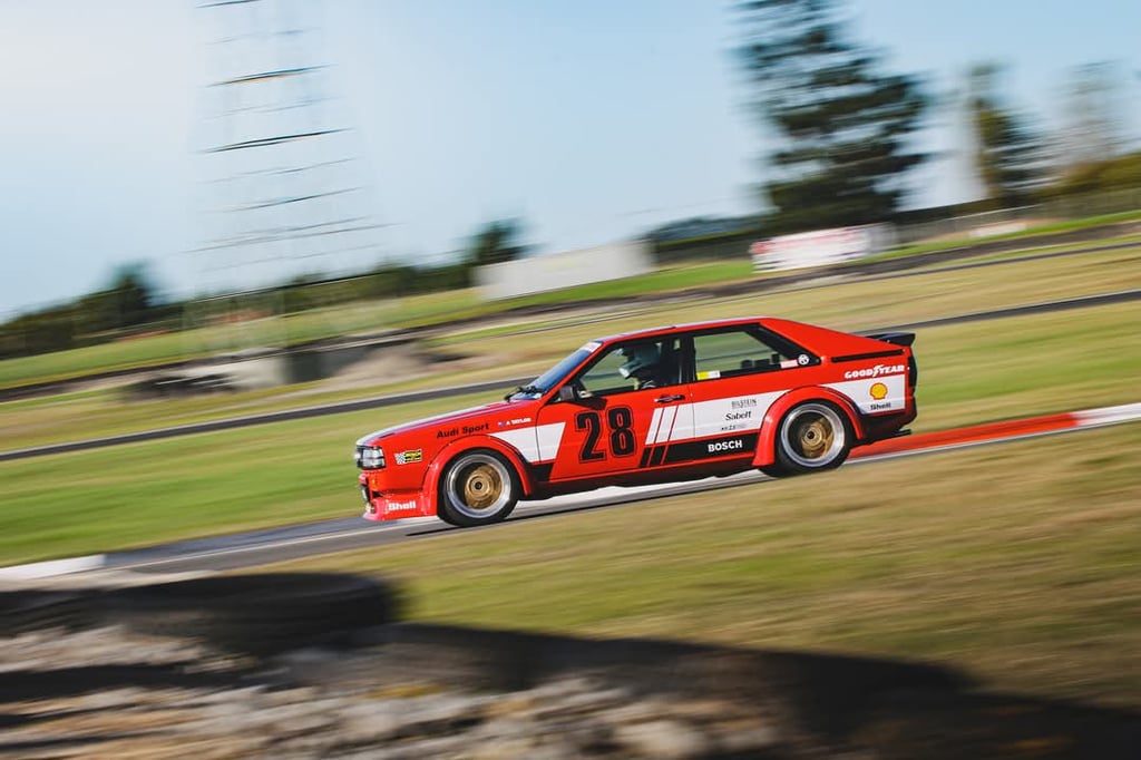 A vintage red Audi Sport Quattro race car speeding on a track with motion blur.