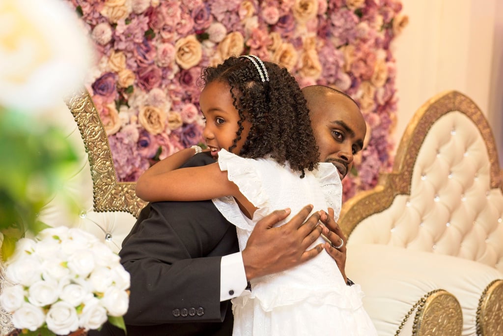 flower girl hugging groom, floral background,, blurry floral in foreground 