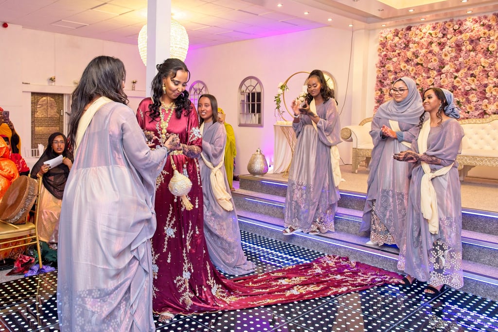 Somalian bride in centre dancing with bridesmaids, all happy and in traditional dresses 