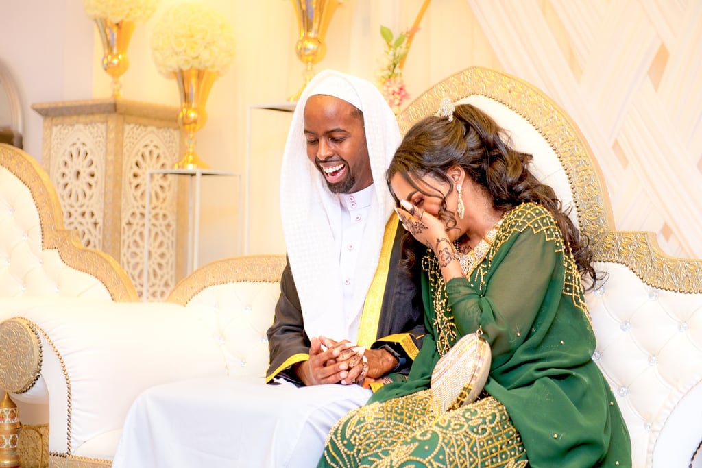 Somalian bride & groom, sitting holding hands laughing and smiling, cream blurred background 