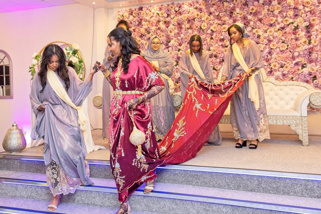 Somalian bridesmaids helping bride off stage, all in traditional vibrant colours dresses 